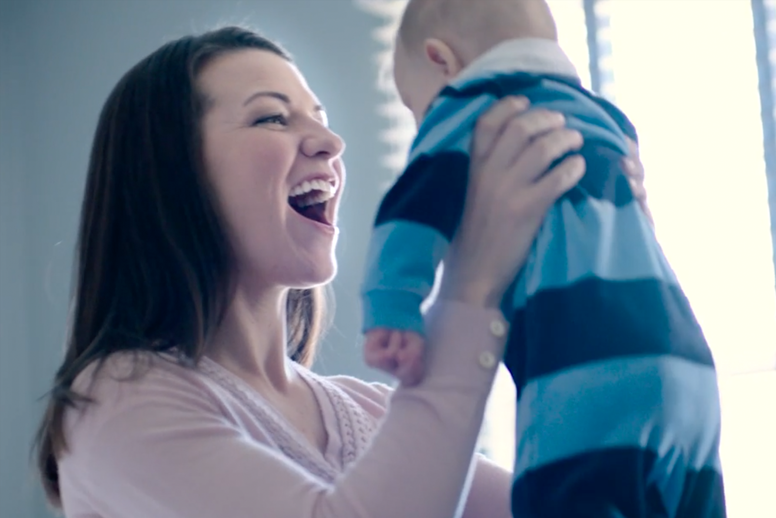 Woman holding up and smiling at her baby